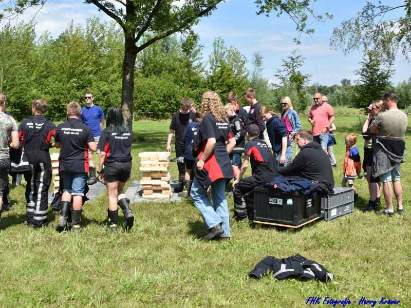 De jeugdbrandweerleden die een oefening aan het doen zijn bij een stapel hout.