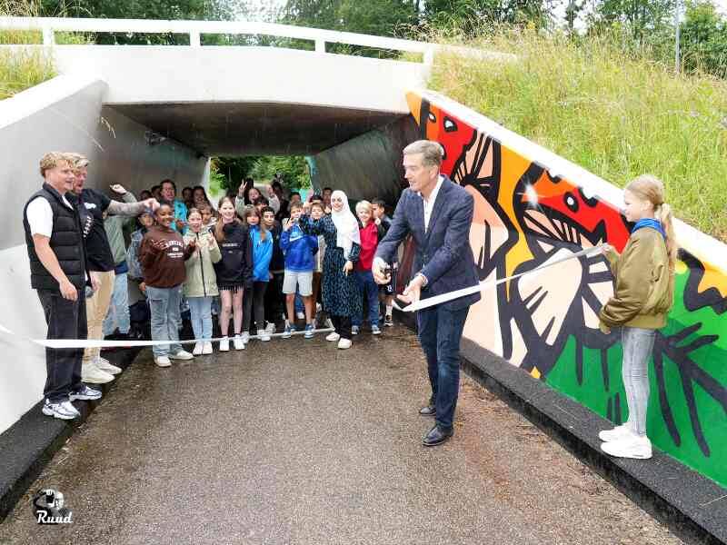 Wethouder vd Beld knipt het lintje bij de tunnel door met alle kinderen en de jongerenwerkers achter het lintje
