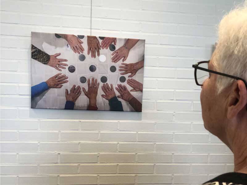 Een dame kijkend naar een van de fotos van de expositie van het wandkleed.
