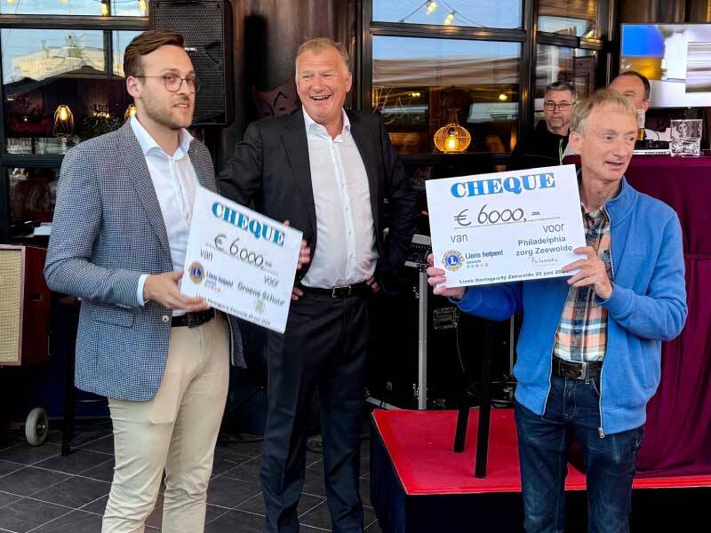 Bestuur van Philadelphia en Groene schuur met cheque in handen met Lions voorzitter op achtergrond