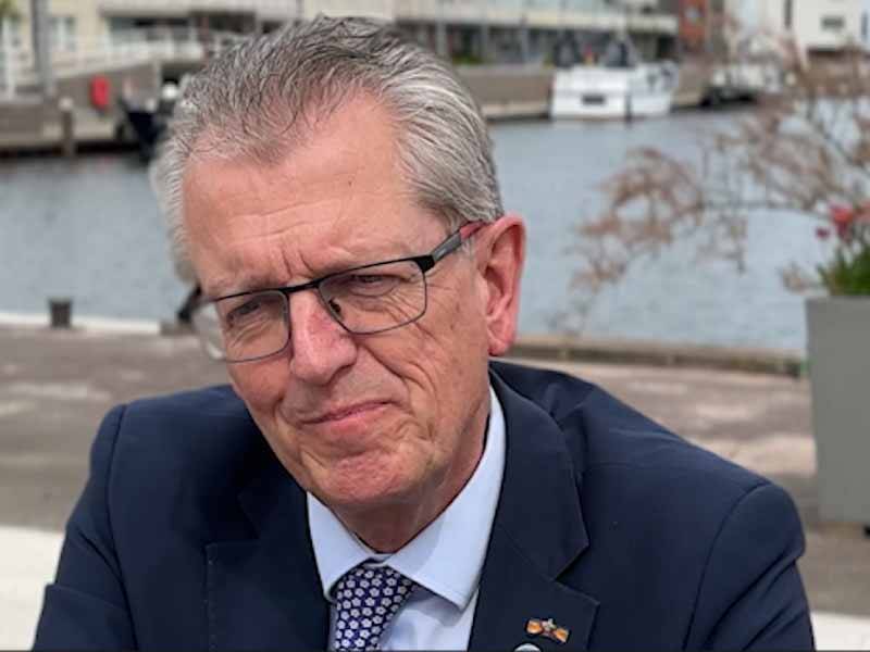 Burgemeester Gorter zittend bij de bankjes in de aanloophaven