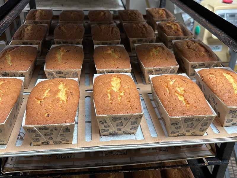 Veel gebakken cakes op een plaat in een ovenkar bij de bakker