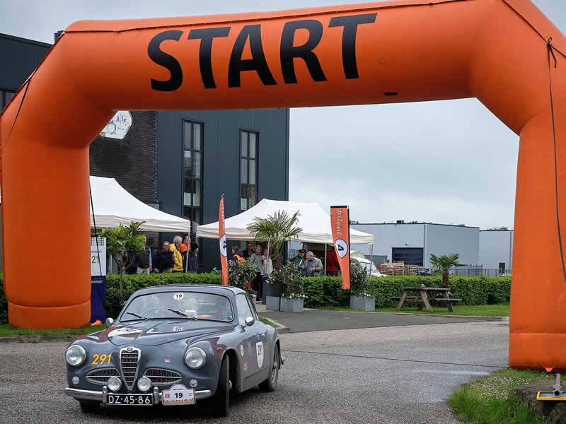 klassieke auto die onder een start boog weg rijd