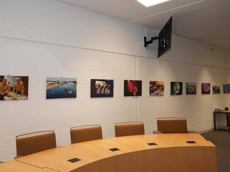 De raadszaal met aan de muur de foto's op een rij