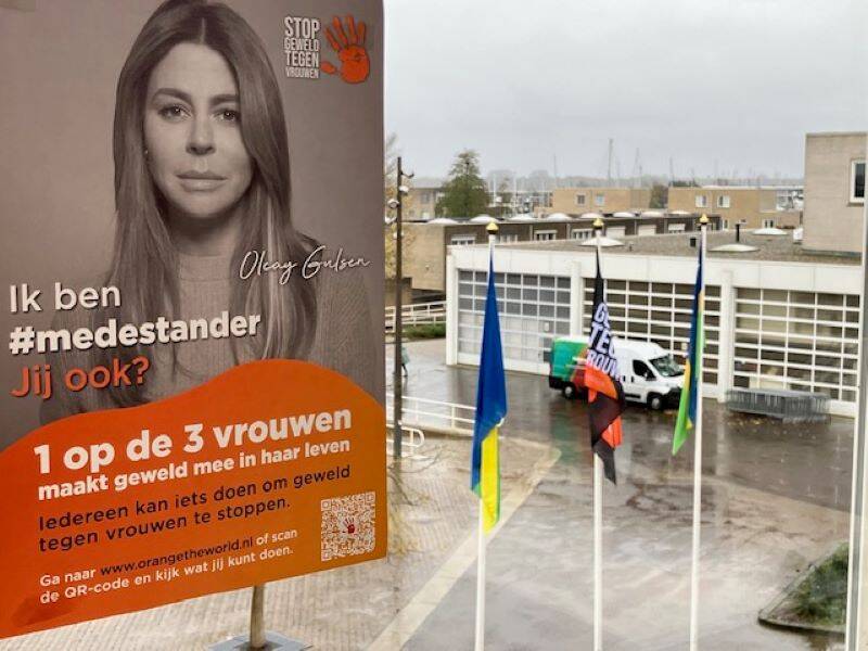 Het raadhuisplein vanaf de bovenverdieping van het gemeentehuis genomen met daar de vlag in de mast en met photoshop de poster van Orange the World