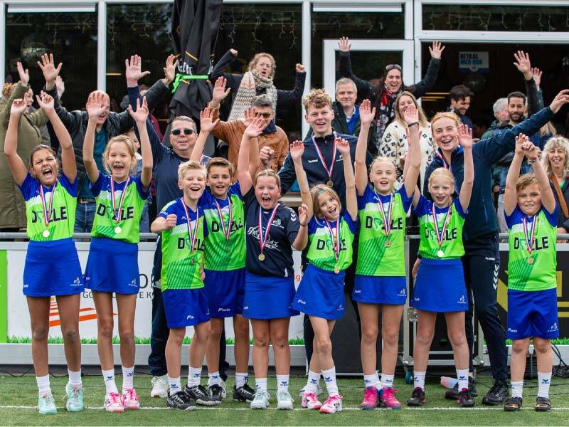 De D1 van KV Wolderwijd juichend met medailles, ouders staan er ook juichend achter