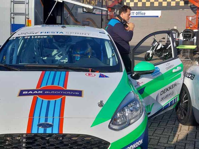 Jenson in de auto met de deur open en een van zijn monteurs erachter