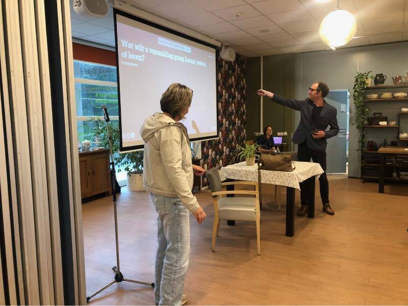 2 presentatoren bij het scherm in de zaal van De Buren