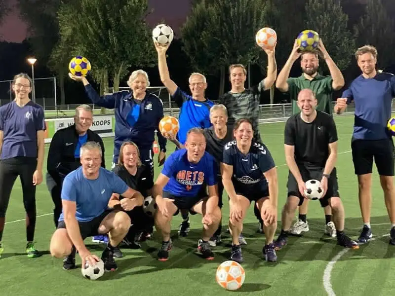 Mensen met korfbal ballen op het grasveld bij de korfbal