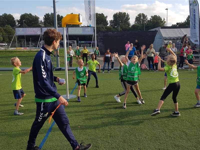 Kinderen op het korfbalveld met een scheids