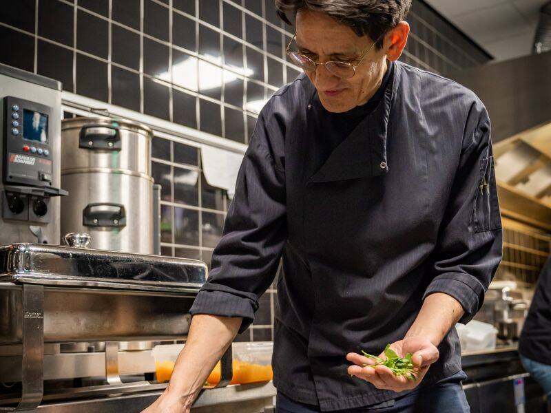 Man in zwarte kokskleding bereid eten