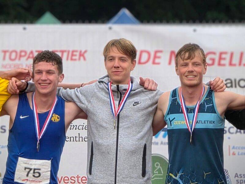 Drie mannen met medailles om staan naast elkaar schouder aan schouder.