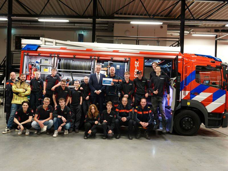 diverse mensen poseren voor een brandweerauto