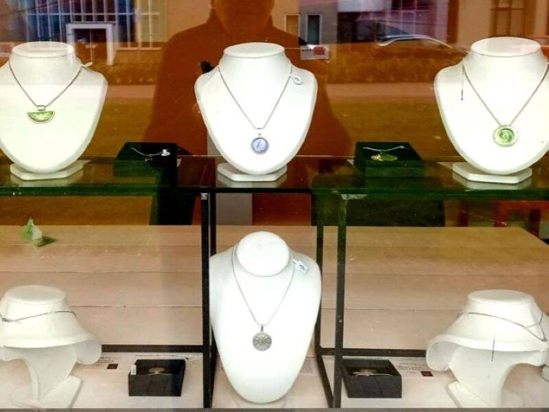 Een etalage met verschillende sieraden tentoongesteld op witte bustes. 