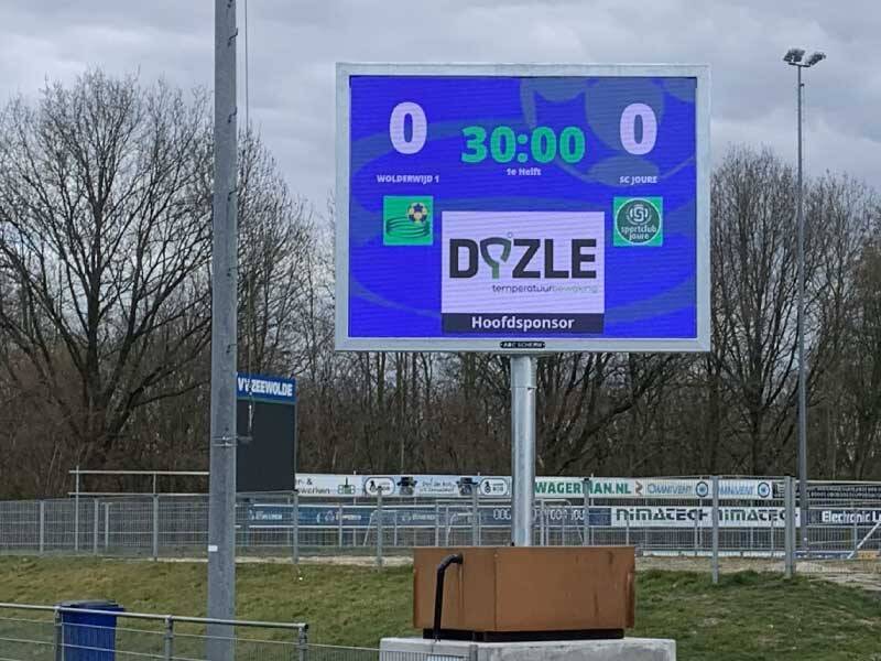Het scorebord op een blok langs het veld met een aankondiging van start van speelhelft