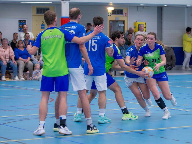 korfbalspelers met een korfbal in een sportzaal op de achtergrond zit publiek