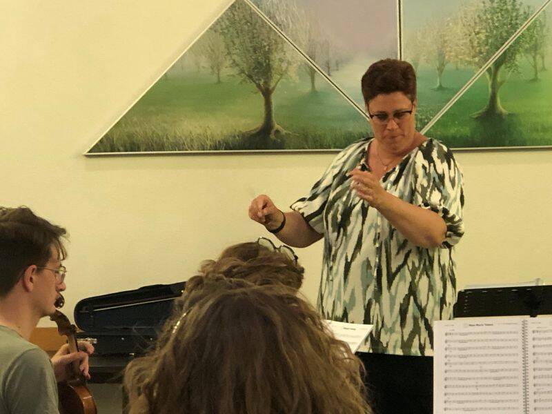Vrouw staat voor mensen met muziekinstrumenten